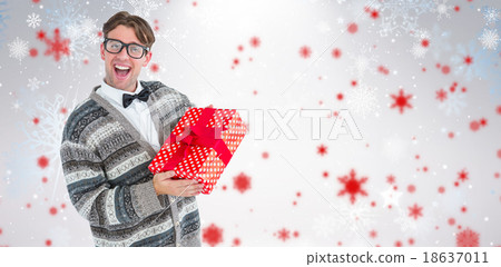 Composite image of happy geeky hipster with wool jacket holding present Composite image of happy geeky hipster with wool jacket holding present 18637011