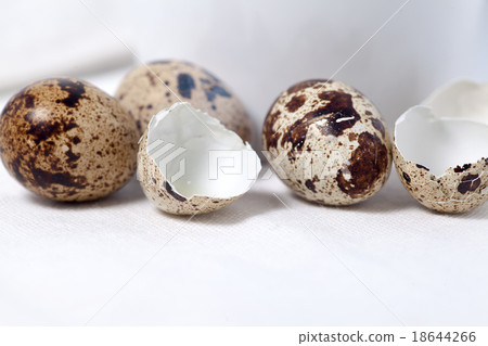 Raw and broken quail eggs on white tablecloth Raw and broken quail eggs on white tablecloth 18644266