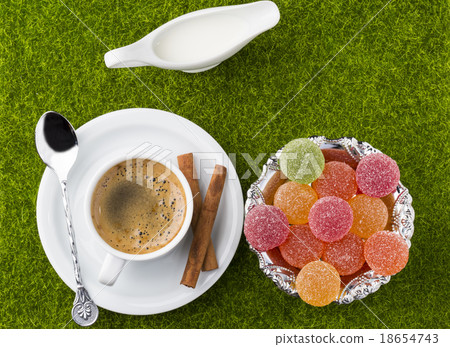 White cup of coffee with dessert on a green grass White cup of coffee with dessert on a green grass 18654743