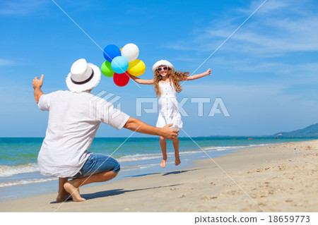 Father and daughter with balloons playing on the beach at the da Father and daughter with balloons playing on the beach at the da 18659773