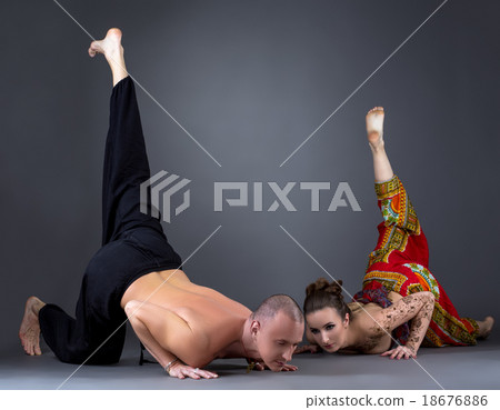 Couple doing yoga in studio, on grey background Couple doing yoga in studio, on grey background 18676886