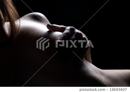 Woman's silhouette holding breast in the dark Woman's silhouette holding breast in the dark 18693607