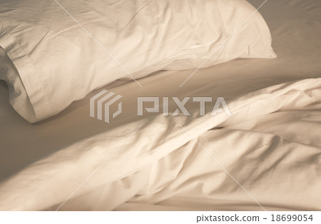 An unmade bed with white linens An unmade bed with white linens 18699054