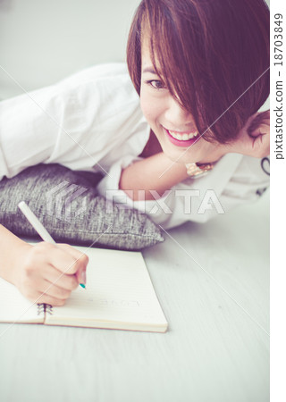 Woman laying on floor and writing love on notebook Woman laying on floor and writing love on notebook 18703849