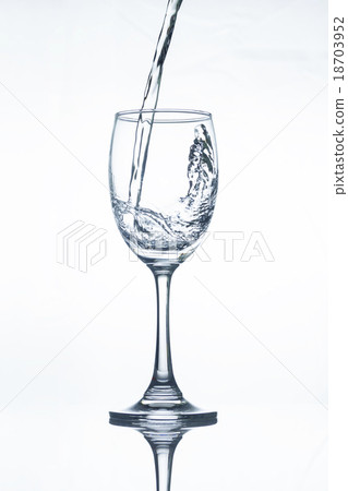 Water pouring into a vine glass on white Water pouring into a vine glass on white 18703952