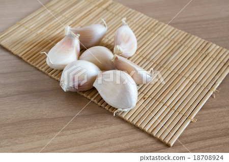 garlic cloves on makisu mat on wood texture 18708924