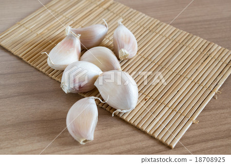 garlic cloves on makisu mat on wood texture 18708925