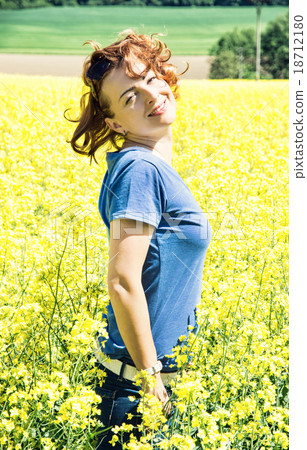 Happy young woman posing in rapeseed field 18712180