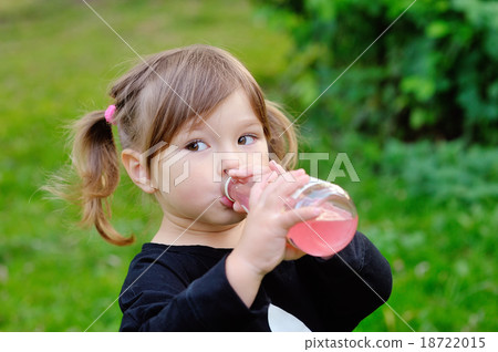 little girl drinking from a bottle of drink 18722015
