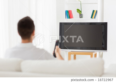 man watching tv and changing channels at home 18722967