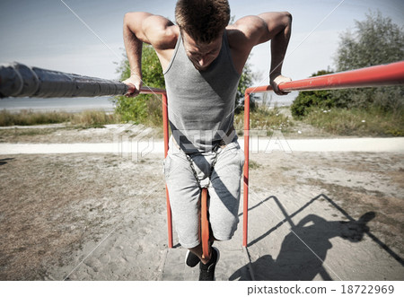 young man exercising on parallel bars outdoors young man exercising on parallel bars outdoors 18722969