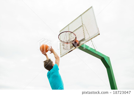 young man playing basketball outdoors 18723047