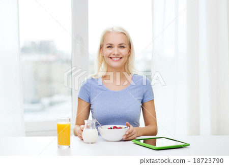 smiling woman with tablet pc eating breakfast 18723790