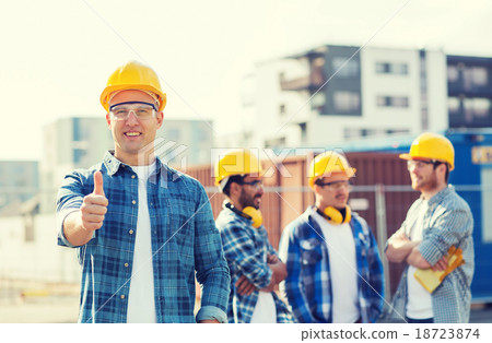 group of smiling builders in hardhats outdoors group of smiling builders in hardhats outdoors 18723874