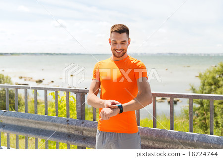 smiling young man with smart wristwatch at seaside smiling young man with smart wristwatch at seaside 18724744