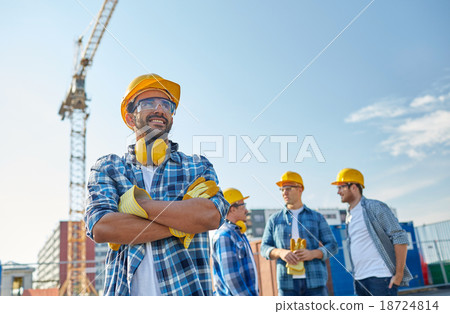 group of smiling builders in hardhats outdoors 18724814