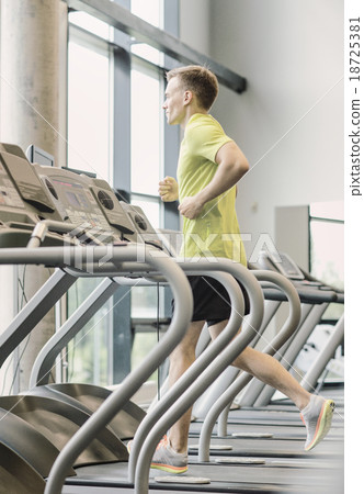 smiling man exercising on treadmill in gym 18725381
