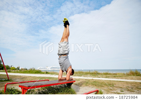 young man exercising on bench outdoors young man exercising on bench outdoors 18725984