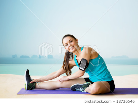 smiling woman stretching leg on mat over pool smiling woman stretching leg on mat over pool 18726546