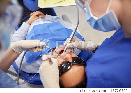 female dentist treating male patient teeth 18726731