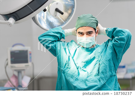 Male surgeon tying mask at operating room 18730237