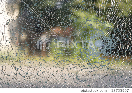 Broken window with a bullet hole in the middle 18735997
