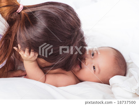 young asian mother and baby in white bed isolated young asian mother and baby in white bed isolated 18737500