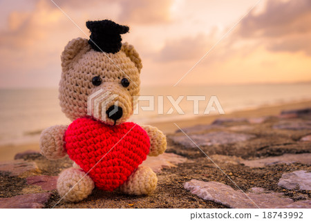 Teddy Bear with red heart sitting near the beach Teddy Bear with red heart sitting near the beach 18743992