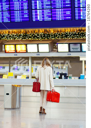 woman at international airport waiting for flight 18764260