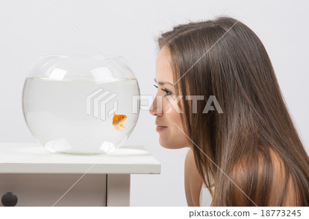 Young girl leaning face to aquarium and looking 18773245