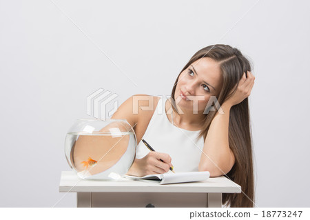 Girl thoughtfully writing in a notebook, standing  18773247