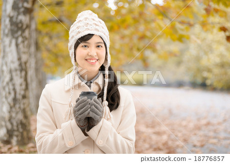 A teenager wearing a coat standing on a tree-lined street of autumn leaves park A teenager wearing a coat standing on a tree-lined street of autumn leaves park 18776857