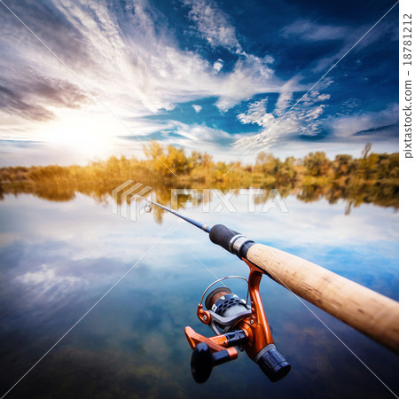 Fishing rod near beautiful pond with cloudly sky Fishing rod near beautiful pond with cloudly sky 18781212