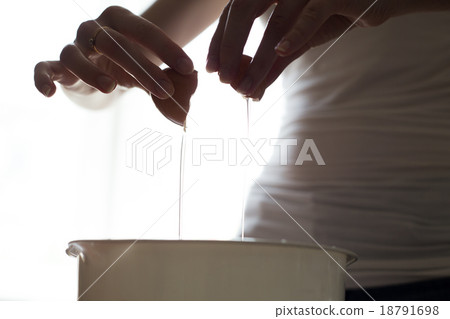 hands opening broken eggshell of brown raw egg 18791698