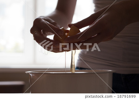 hands opening broken eggshell of brown raw egg hands opening broken eggshell of brown raw egg 18791699