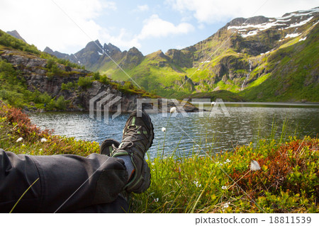 Hiker resting near mountain lake Hiker resting near mountain lake 18811539