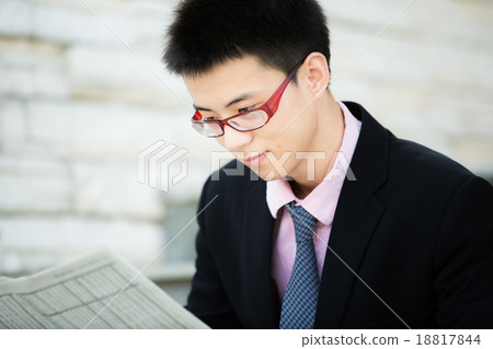A young businessman reading newspaper A young businessman reading newspaper 18817844