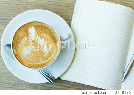 Hot latte art coffee cup on wooden table and note book, vintage Hot latte art coffee cup on wooden table and note book, vintage 18818150
