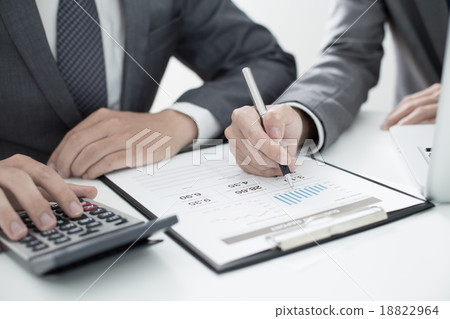 Two businessmen looking at report and having a discussion in off Two businessmen looking at report and having a discussion in off 18822964