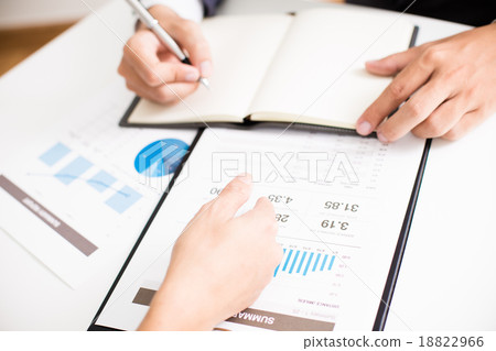 Two businessmen looking at report and having a discussion in off Two businessmen looking at report and having a discussion in off 18822966