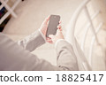 Young businessman using a phone sitting on the stairs 18825417