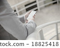 Young businessman using a phone sitting on the stairs 18825418