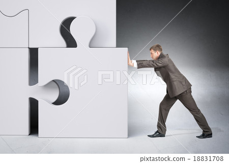 Man in suit pushing grey puzzle piece Man in suit pushing grey puzzle piece 18831708