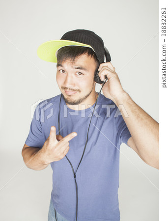 young asian man in hat and headphones listening 18832261