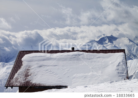 Snowy roof and mountains in clouds 18833665