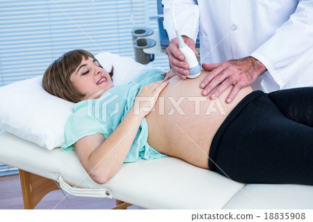 Doctor performing ultrasound on smiling woman 18835908
