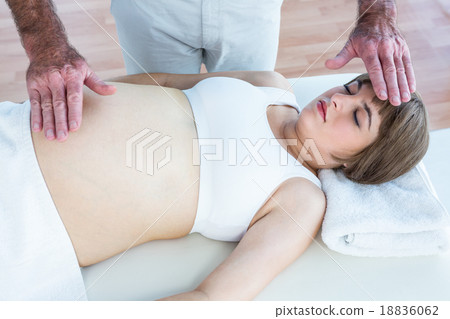 Pregnant woman getting reiki from male therapist Pregnant woman getting reiki from male therapist 18836062