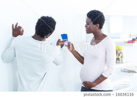 Wife holding color swatches while talking to husband Wife holding color swatches while talking to husband 18836116