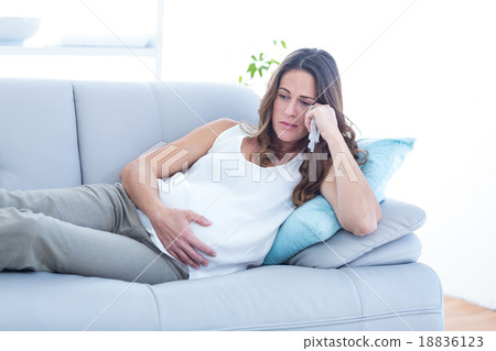 Sad pregnant woman lying on sofa Sad pregnant woman lying on sofa 18836123