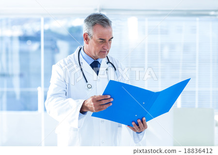 Male doctor reading document in hospital Male doctor reading document in hospital 18836412